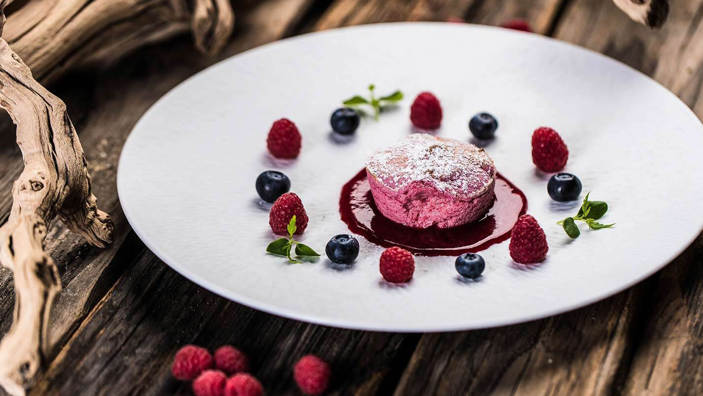 Dessert mit einem rosa Törtchen und Himbeeren und Schwarzbeeren - Hotel Patriarch