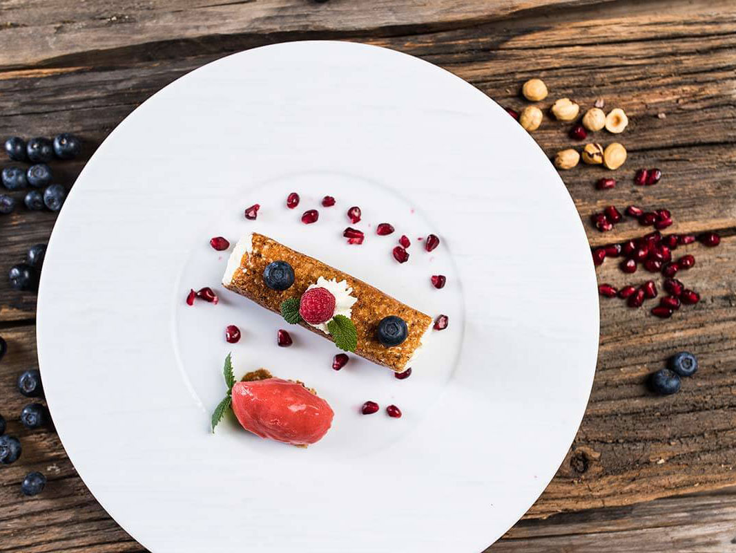 Dessert mit einem Sorbet, einem länglichen Törtchen und Granatapfelkerne - Hotel Patriarch
