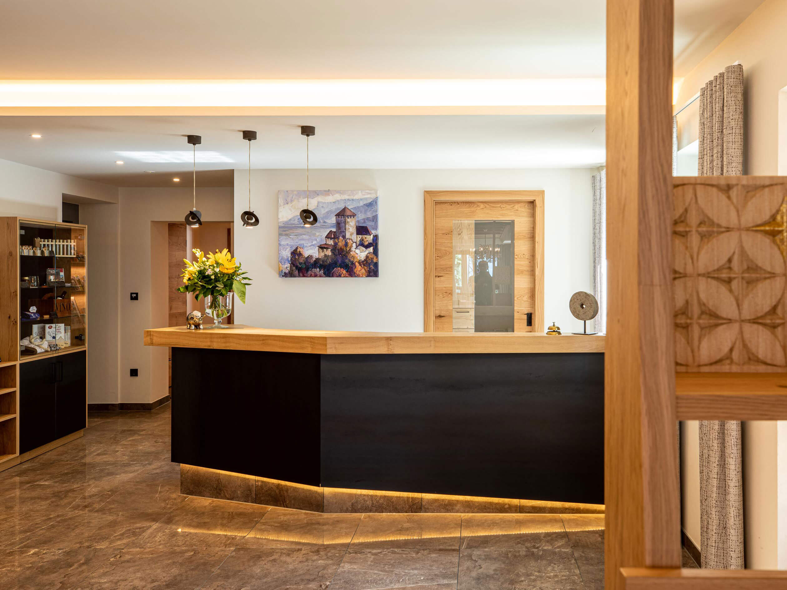 Rezeption mit Theke aus Holz, schwarzen Elementen und indirekter Beleuchtung - Hotel Patriarch
