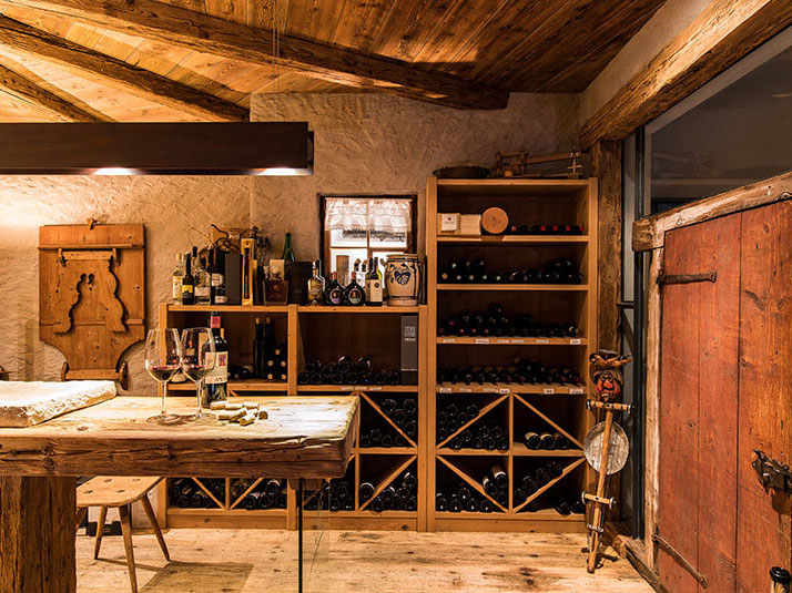 Der Weinkeller mit verschiedenen Weinregalen und einer Verkostungstheke mit einer Flasche Wein und zwei Gläser - Hotel Patriarch