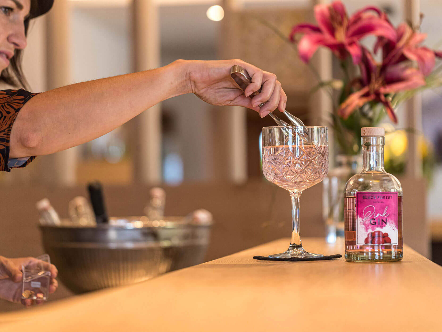 Die Servicefachkraft serviert einen rosaroten Gin Tonic an der Bar - Hotel Patriarch