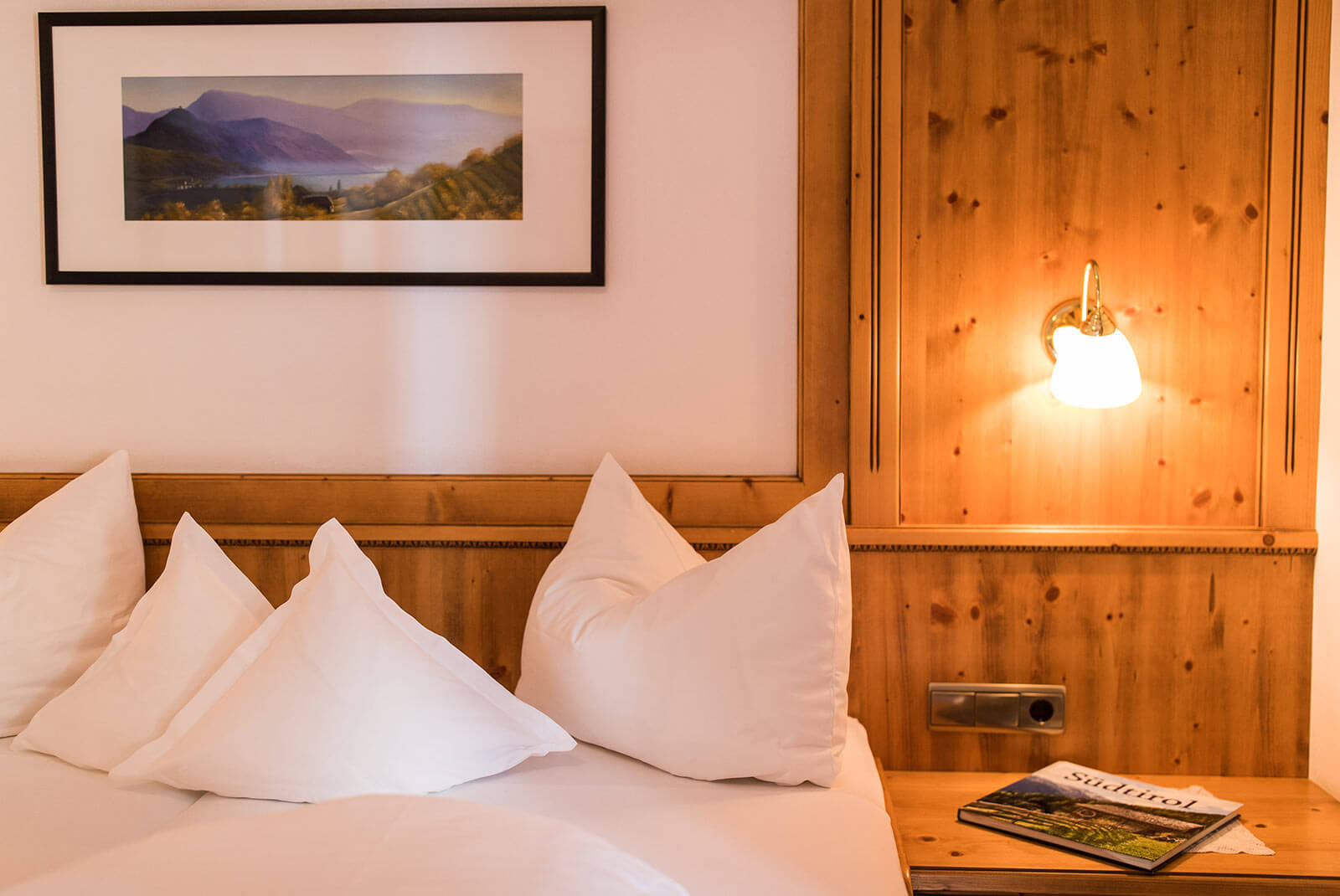 Bett mit weißer Bettwäsche und einem Landschaftsbild drober im Einzelzimmer Appartement - Hotel Patriarch