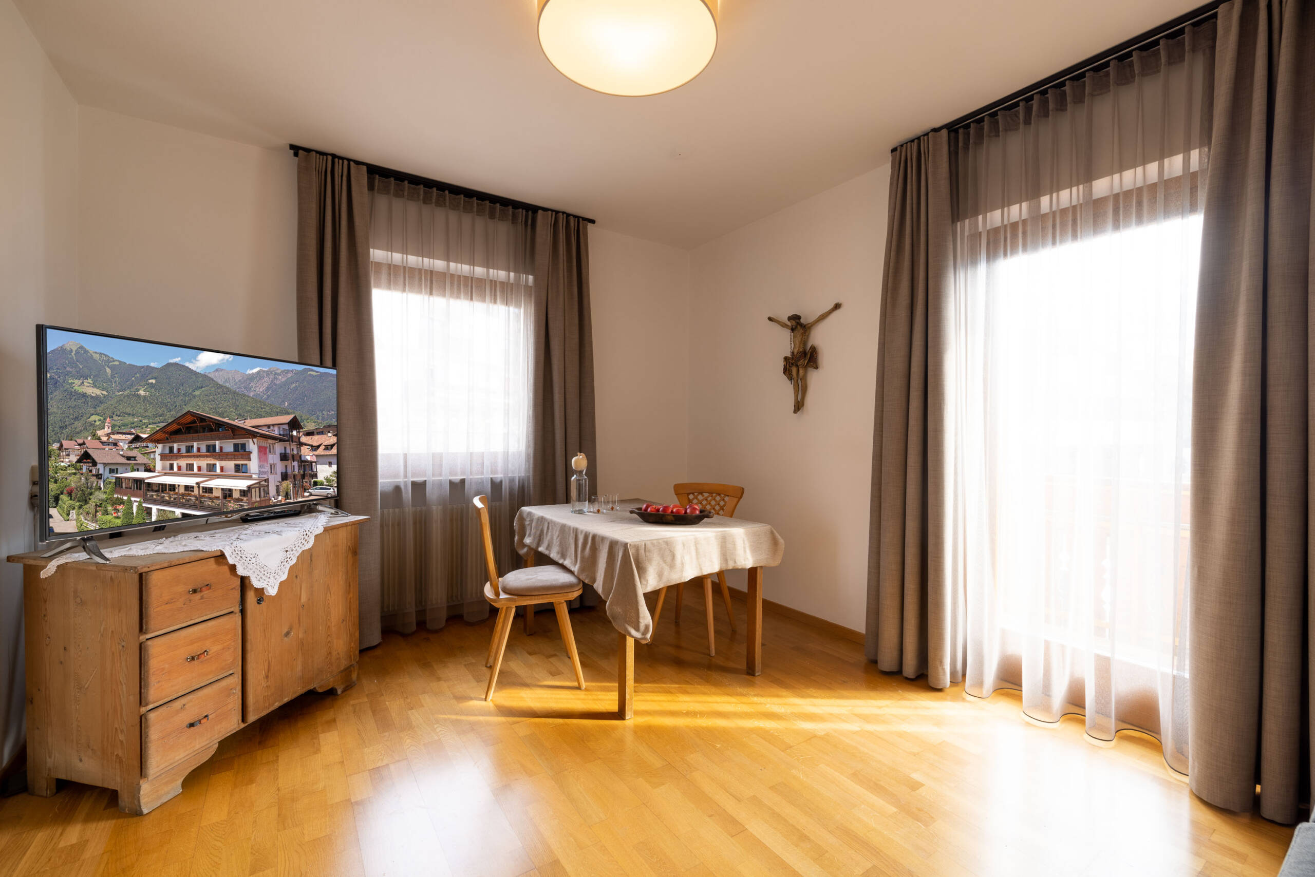 Wohnzimmer mit Fernseher und einem Tisch mit Stühlen in der Ferienwohnung mit Hotelservice - Hotel Patriarch