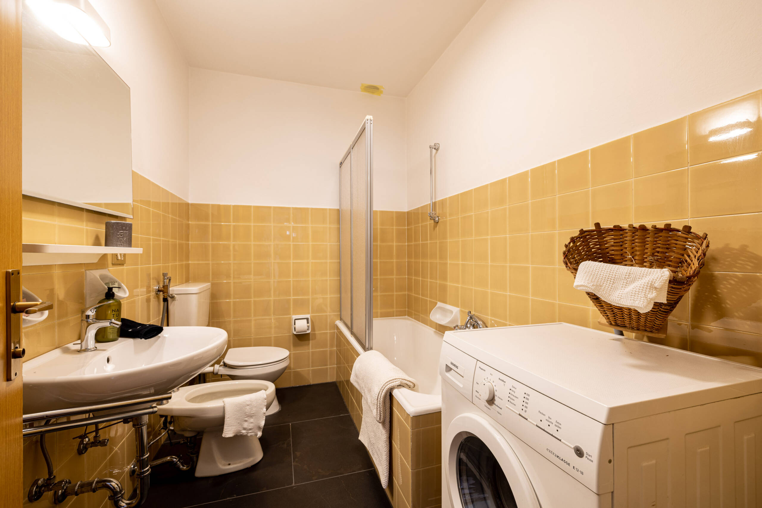 Badezimmer mit Badewanne und Waschmaschine in der Ferienwohnung mit Hotelservice - Hotel Patriarch