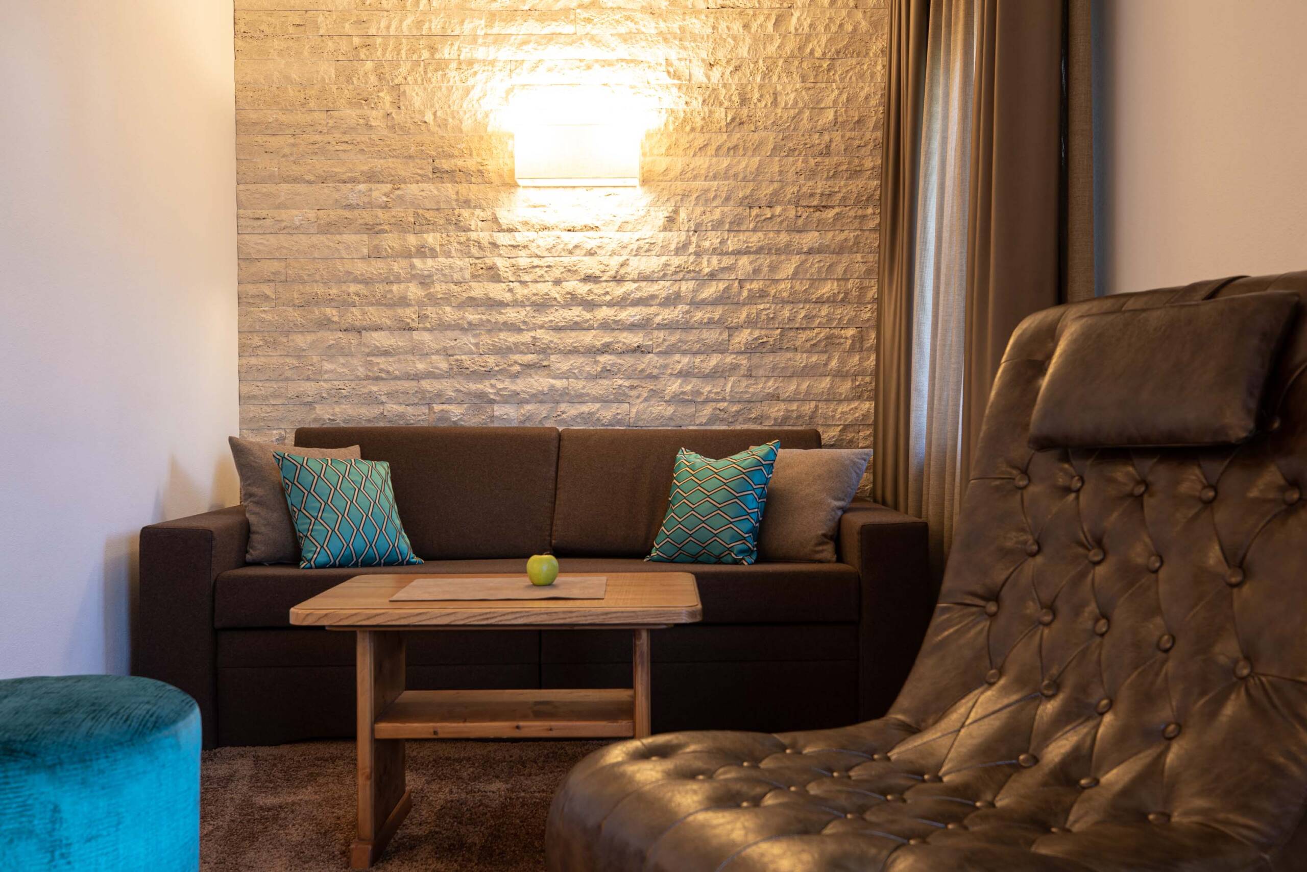 Wohnbereich mit dunkelbraunen Sofa und blauen Kissen in der Mutspitz-Suite - Hotel Patriarch