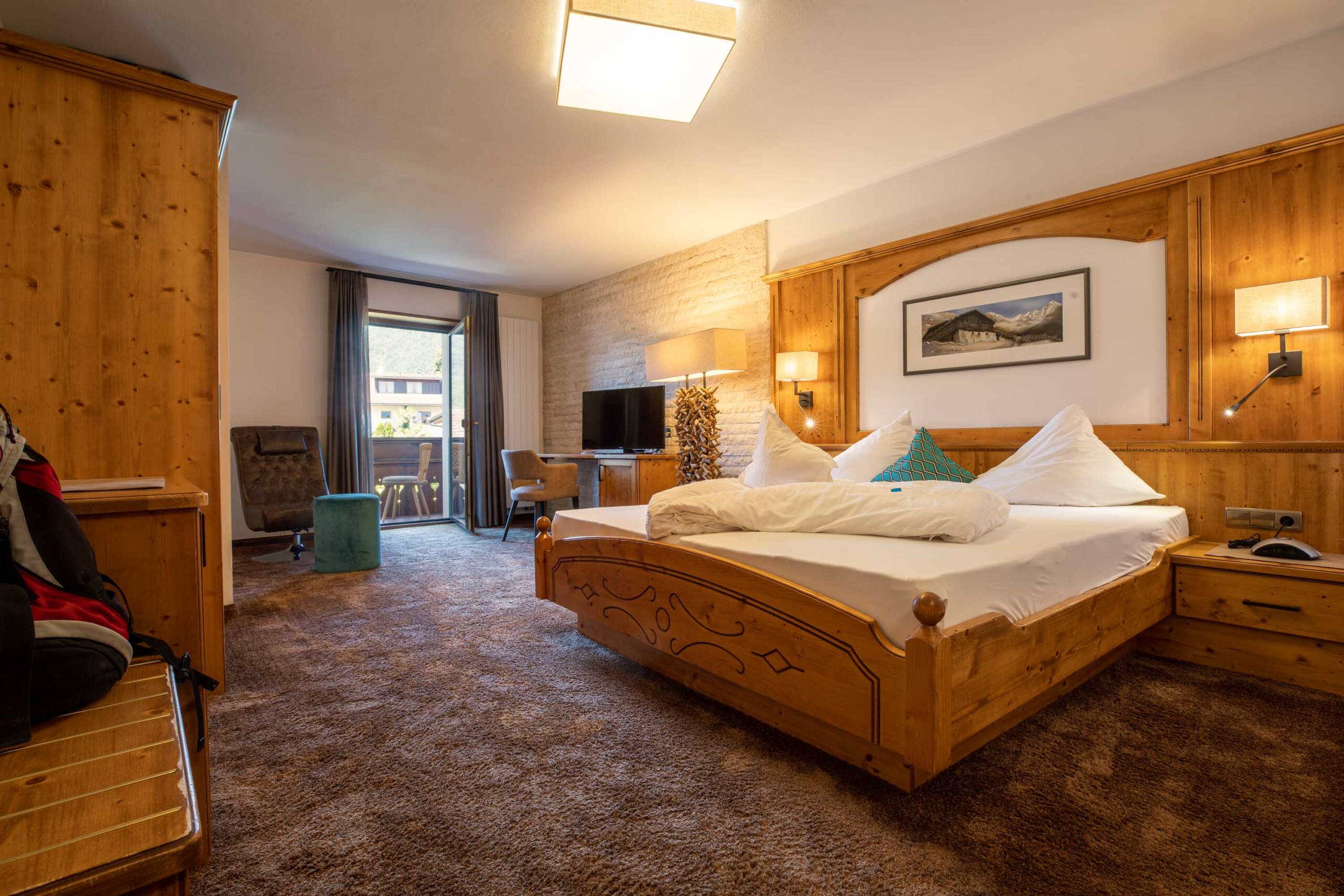 Schlafbereich mit Doppelbett und Wohnbereich mit Balkon in der Mutspitz-Suite - Hotel Patriarch