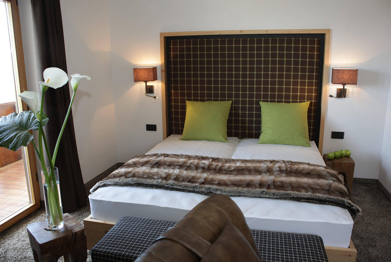 Doppelbett mit grünen Kissen im Schlafzimmer der Rosensuite zur Sonnenseite - Hotel Patriarch