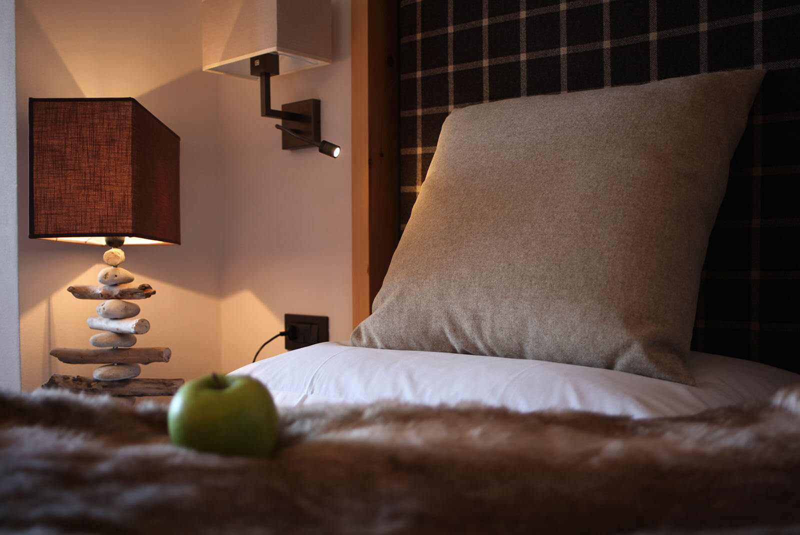 Detailaufnahme vom Bett mit grauem Kissen und einem grünen Apfel im Sonnenzimmer - Hotel Patriarch